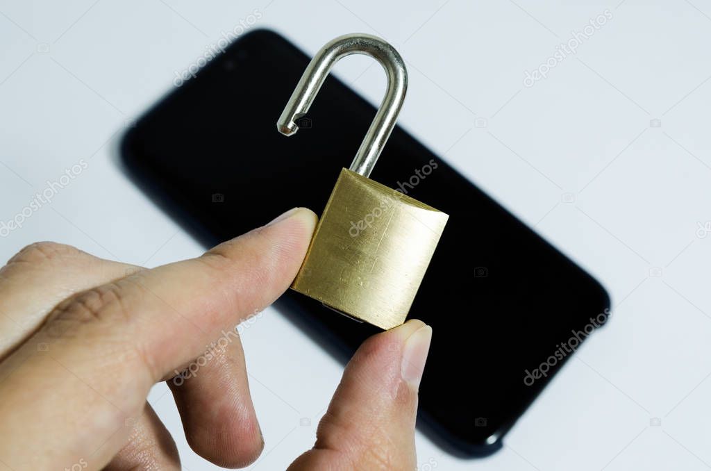Conceptual photo of security on mobile phones. Hand holding a open padlock and a cell phone in the background