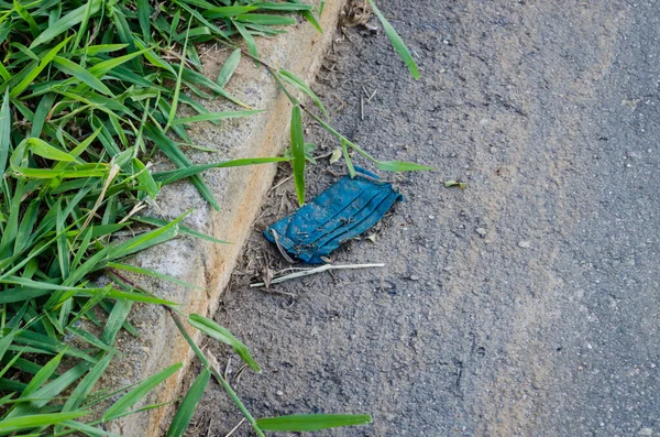 道路に捨てられた青の使い捨てマスクを植物の隣に撒き散らし — ストック写真