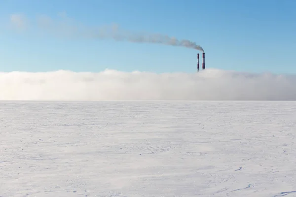 Smokestacks in the fog on a frozen lake. Pollution. Harmful emissions/
