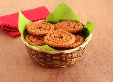 Bir geleneksel, popüler, vejetaryen ve ahşap arka plan üzerinde bir sepette bir muz yaprak üzerinde bazı festivaller sırasında yapılan lezzetli Hint lezzetli snack, genellikle, Chakli veya chakkuli olduğunu.