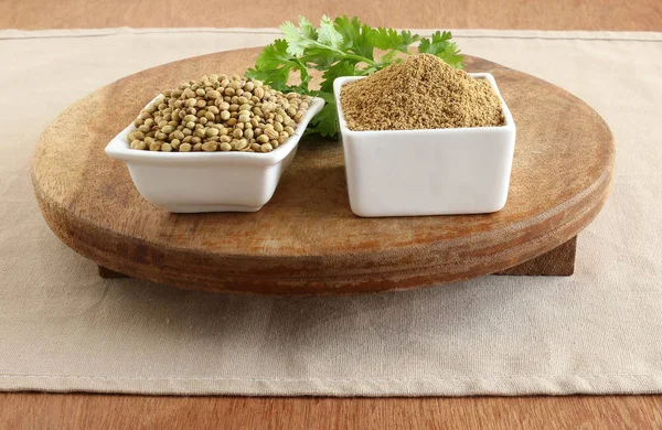 Ahşap bir masa üzerinde pişirme bir madde olduğunu kişniş toz, kişniş ve yaprakları,