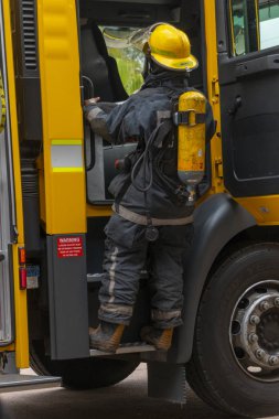 A görünüm üzerinde bir sarı itfaiye orada tam üniformalı ve oksijen tüpü tırmanma bir itfaiyeci arkasında