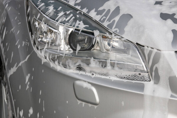 A Close up of soap foam on the left side of the main light of a sliver car