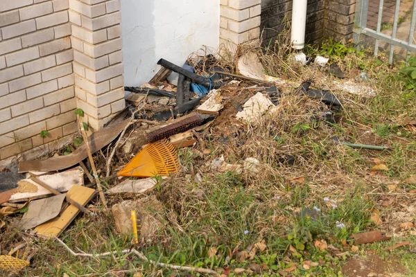 Dağınık çöp olsa da ve ele büyüyen uzun yeşil çim bir binanın yan tarafındaki