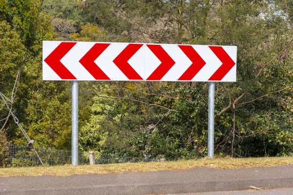 A close up view of a chervron direction sign on the side of a main raod