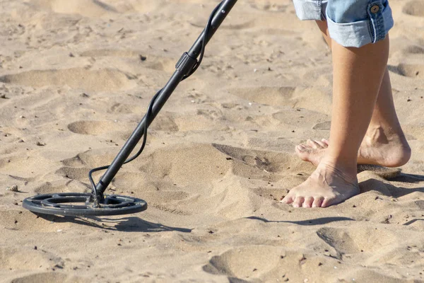 Bir kişi ayakları ve metal nesneler sahil kumu altında arıyorum bir metal detektörü alt görünümü kadar yakın 