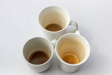 Bir gruptaki üç kirli beyaz kahve bardağı üstten görünüm izole beyaz zemin üzerinde bir yakından 