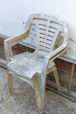 İki çok eski beyaz plastik sandalyeler yan bir metal merdiven ve beyaz duvar karşı görünümünü yakından