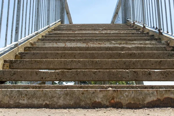Görünüm eski ve paslı beton ve metal bir merdiven Demiryolları hatları üzerinden bir köprüye giden yakından 