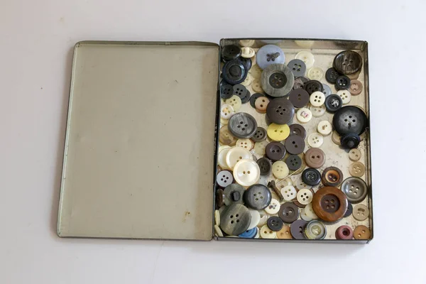 İzole beyaz zemin üzerinde farklı boyutu ve rengi düğmeleri ile eski bir metal kutusunun görünümü kadar yakın 