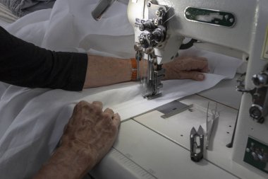 Bir kadın açık yan görünüm yakından ekme beyaz keten kumaş bir endüstriyel makine üzerinde eller 