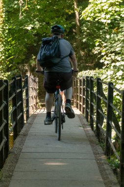 Bristol-Haziran-2020-İngiltere-yakın çekim bir adam bisiklet üzerinde kamu ormanı üzerinde küçük bir köprü üzerinde 