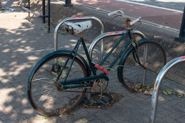 Bristol-June-2020-England-a close up view of a rusted old bicycle that has been abandoned and locked to a bike rake in the city