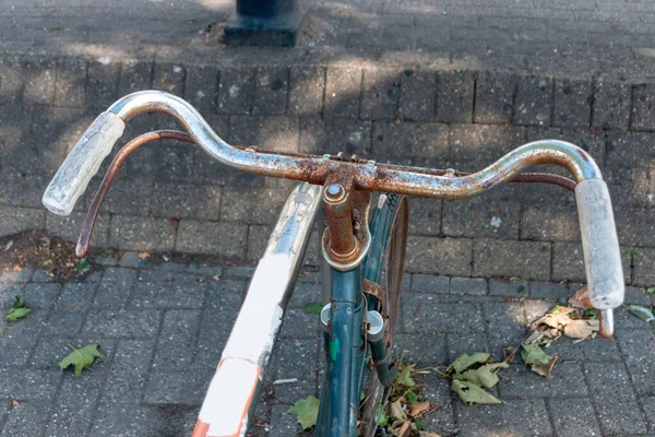 市内の自転車の熊手に放置されロックされている錆びた古い自転車を間近に見ることができます — ストック写真