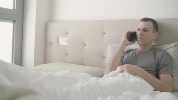 Szczęśliwy Człowiek Odpowiadając Jego Telefon Leżąc Łóżku — Wideo stockowe