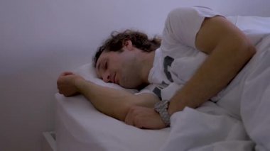 Yakın çekim Genç adam evde yatakta uyuyor, onun gözlük ve yataktan kalkmak