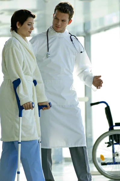男性医師が女性患者を病院で松葉杖歩行支援 — ストック写真