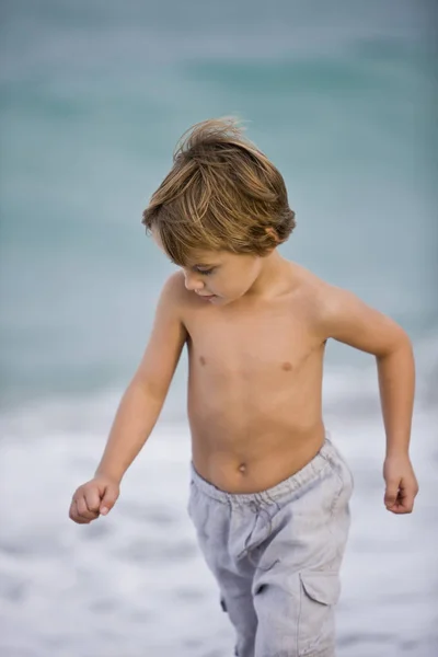 无衬衫的小男孩走在沙滩上 往下看 — 图库照片