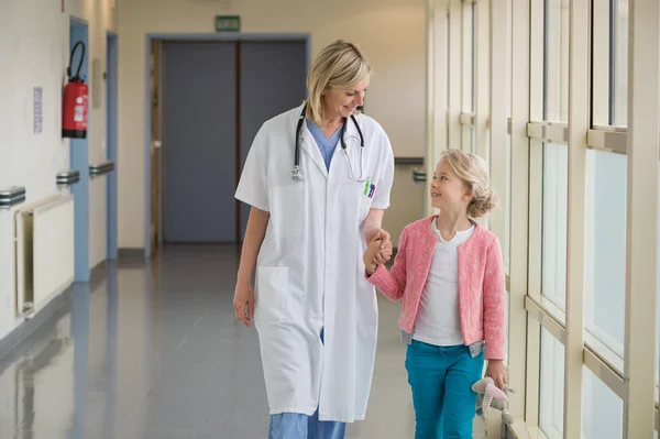 女医生和一个女孩在医院走廊里散步 — 图库照片