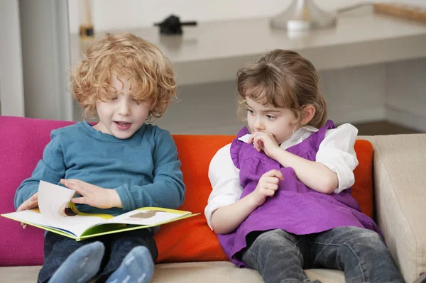 Junge Sitzt Mit Seiner Schwester Und Liest Ein Buch — Stockfoto