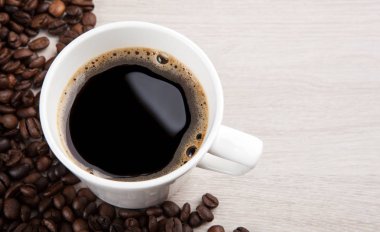 beyaz fincan kahve köpüklü kızarmış kahve çekirdekleri çerçevede bir yakın çekim