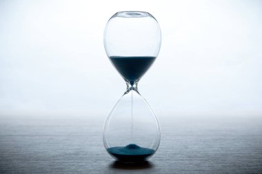 beyaz bir arka plan ve gri bir masa mavi kum kum saati kapat