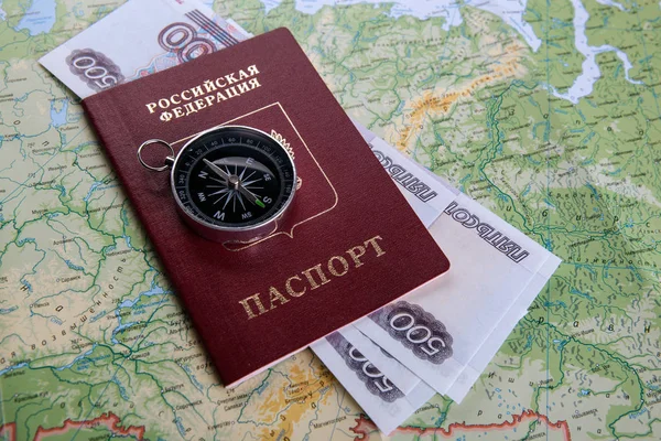 Russian passport with a compass and Russian money on a geographical map close up