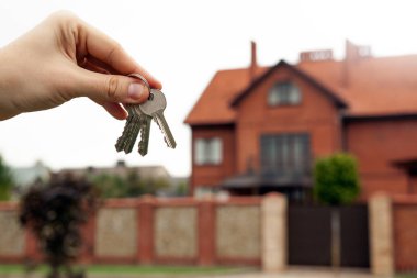 Bir adamın elini anahtarları yeni binalar arka plan üzerinde tutar.