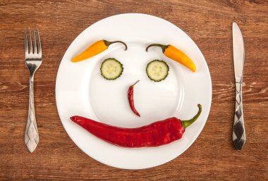 top görünüm Chili biber ve salatalık dilimleri gülümseme ile mutfak eşyaları beyaz tabakta şeklinde