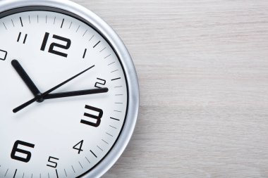 Beyaz saat yüzünü bir ahşap gri arka plan portre siyah rakamlar ile