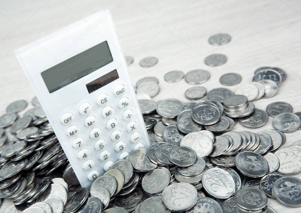 white calculator with russian ruble silver coins close up