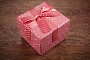 bir pembe hediye kutusu ahşap arka plan üzerinde bir yay ile yakın çekim