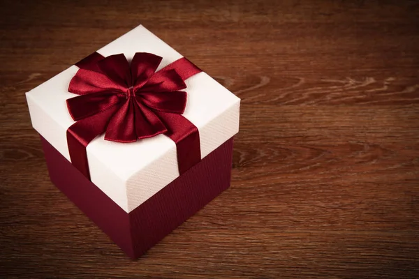 白色礼品盒与红色弓在木背景关闭 — 图库照片