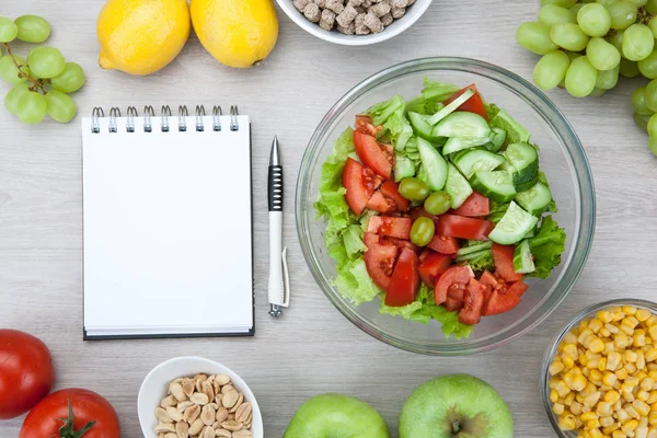 notebook with a diet plan with fresh vegetables and fruits and a