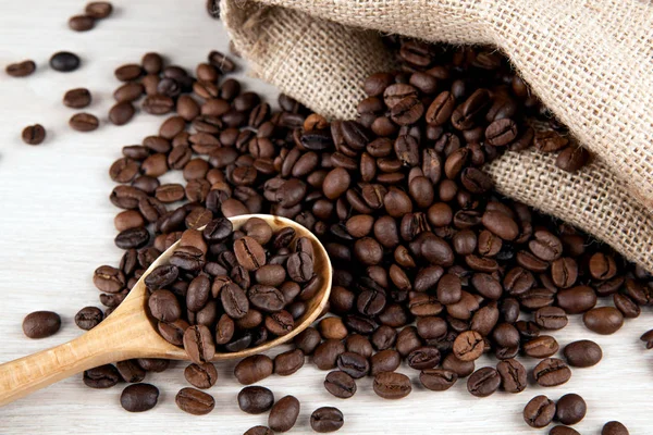 Cuchara de madera y granos de café tostados y bolsa de café de cerca —  Fotos de Stock