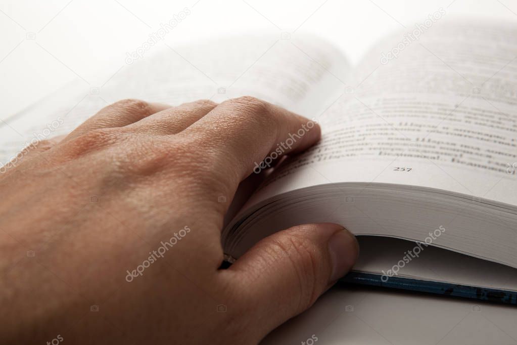 man's hand on an open book with white pages