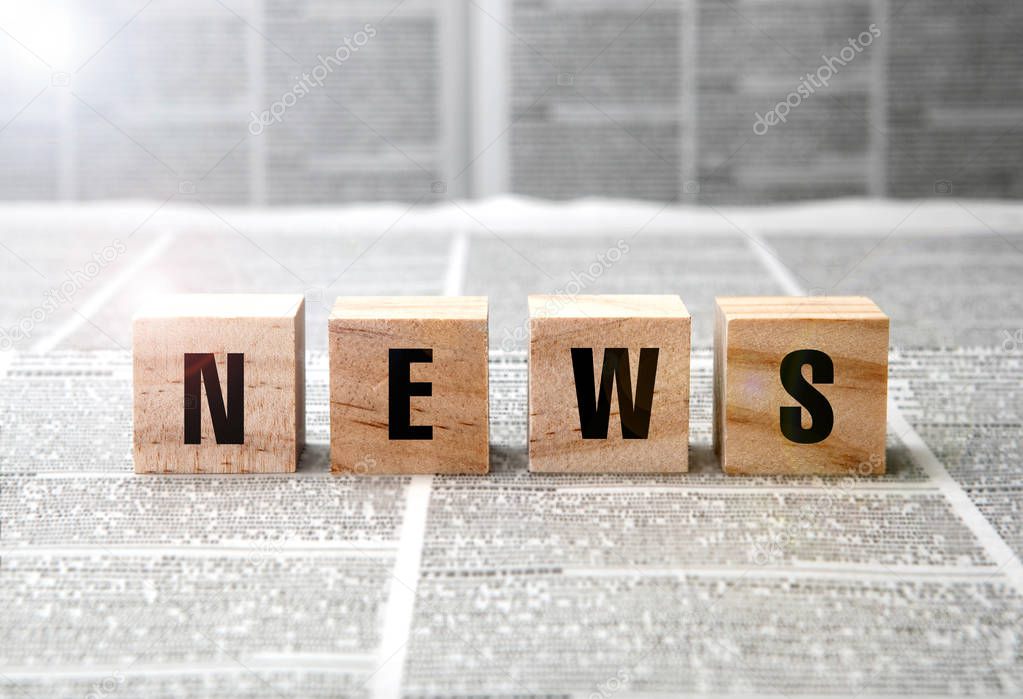 News title on square wooden blocks on a newspaper background