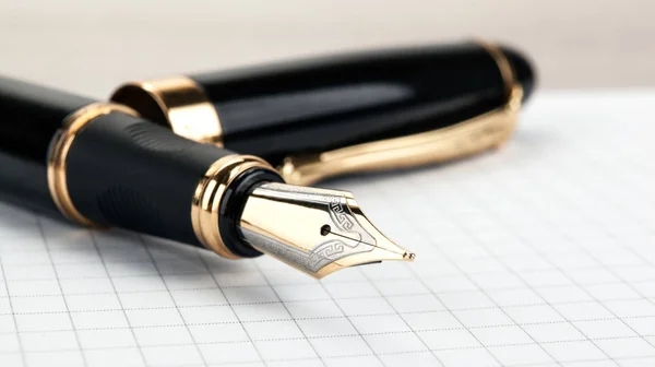 Золотая ручка на блокноте на столе — стоковое фото