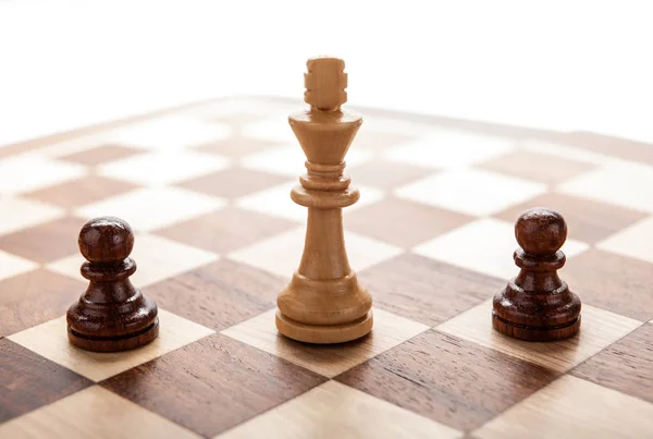 Wooden white chess king between black pawns — Stock Photo, Image