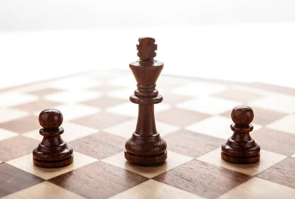 Wooden black chess king between black pawns — Stock Photo, Image