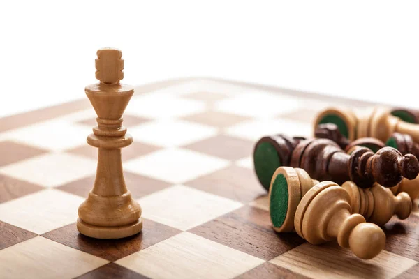 Rei do xadrez com peças de xadrez espalhadas em um tabuleiro de xadrez de madeira — Fotografia de Stock