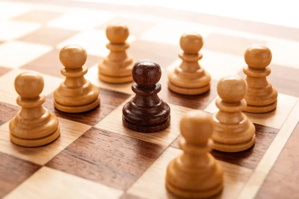 Black chess pawn surrounded by white chess pawns — Stock Photo, Image