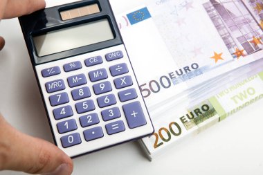 Elinde hesap makinesi ve bir tomar banknot var. 500 ve 200 avro.