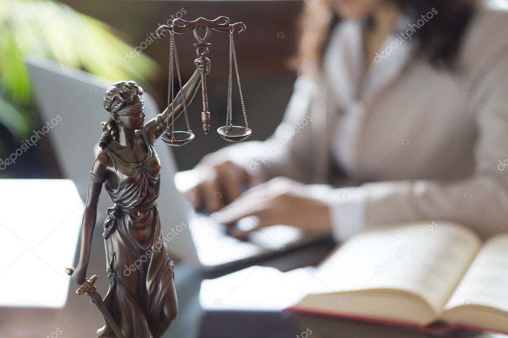 Lawyer office. Statue of Justice with scales and lawyer working on a laptop. Legal law, advice and justice concept