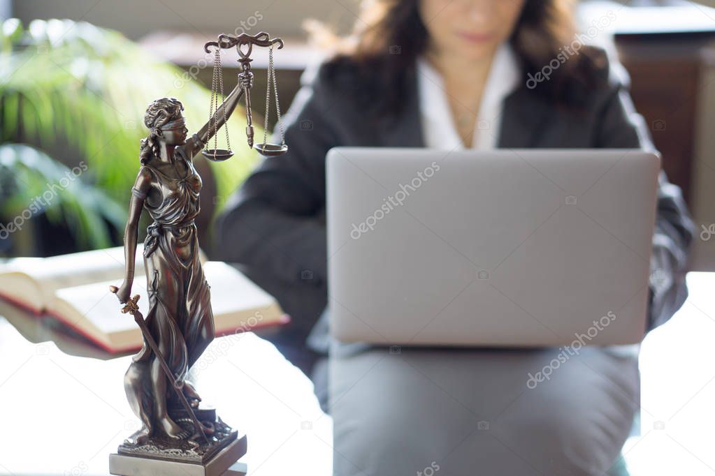 Lawyer office. Statue of Justice with scales and lawyer working on a laptop. Legal law, advice and justice concept