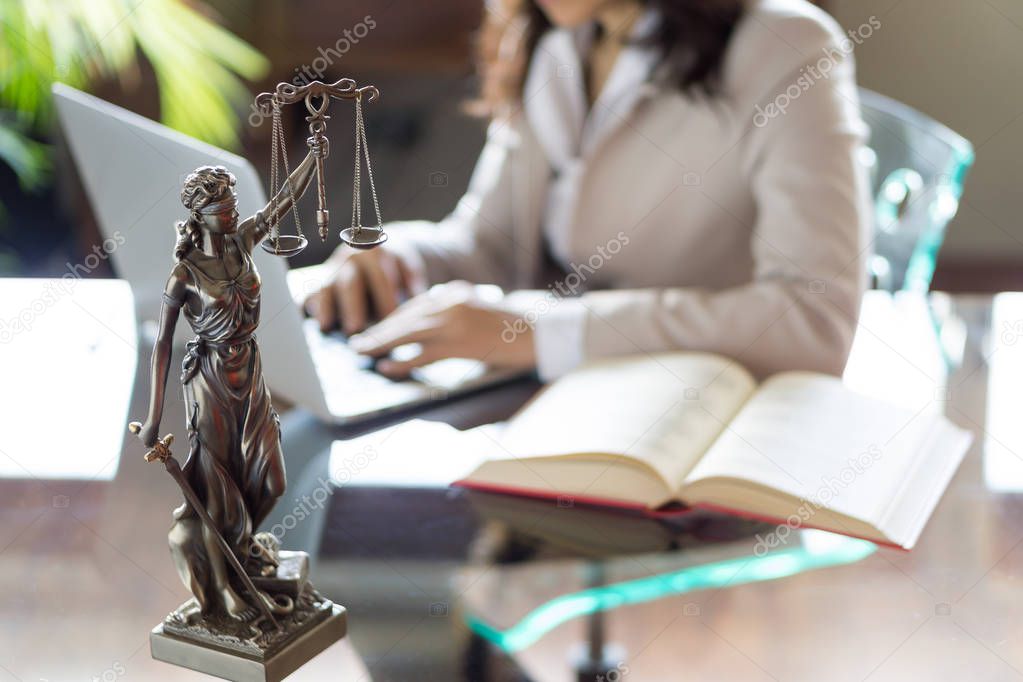 Lawyer office. Statue of Justice with scales and lawyer working on a laptop. Legal law, advice and justice concept