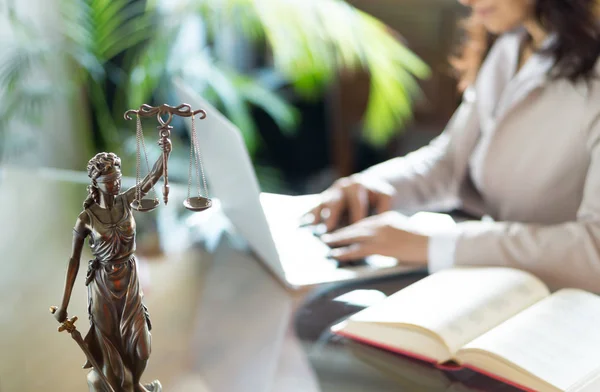 Юридический офис. Статуя правосудия с весами и адвокатом, работающим над ноутбуком . — стоковое фото