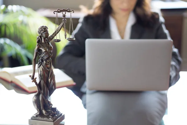 Юридический офис. Статуя правосудия с весами и адвокатом, работающим над ноутбуком . — стоковое фото