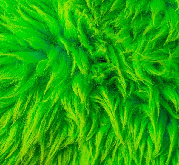 Modern neon green colored soft hairy fur on a animal skin carpet macro closeup texture background