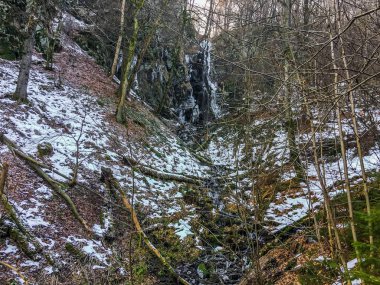 Buz sarkıtları ve akış su Wasserfall Almanya'nın orman ortamındaki biraz donmuş şelale